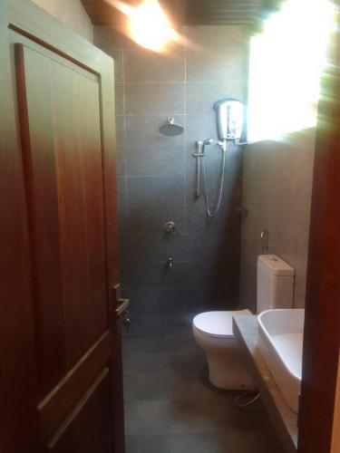 a bathroom with a shower and a toilet and a sink at Club Mango Resort in Kalpitiya