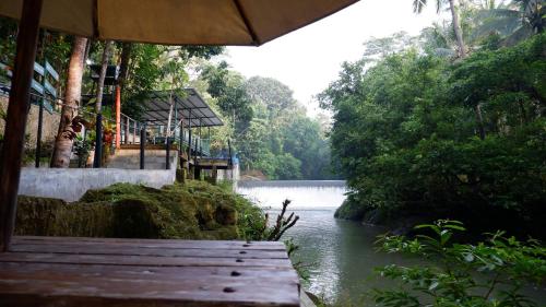 a view of a river with a wooden bench at Hau Eco Lodges Citumang Pangandaran in Pangandaran