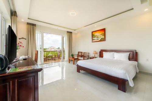 a bedroom with a bed and a television and a balcony at Hoi An Palmy Villa in Hoi An
