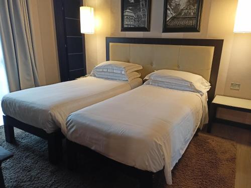 two beds in a hotel room with white sheets at c-hotels Ambasciatori in Florence