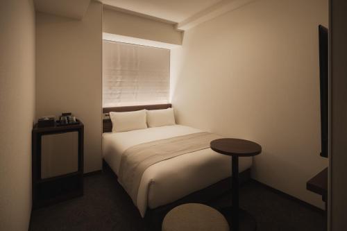 a small bedroom with a bed and a small stool at Nest Hotel Tokyo Yaesu in Tokyo