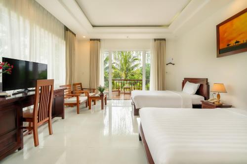 a hotel room with two beds and a television at Hoi An Palmy Villa in Hoi An