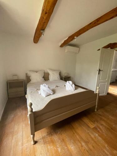 Cette chambre comprend un lit avec des draps blancs et du parquet. dans l'établissement Le mas de la Cognasse, aux Arcs-sur-Argens