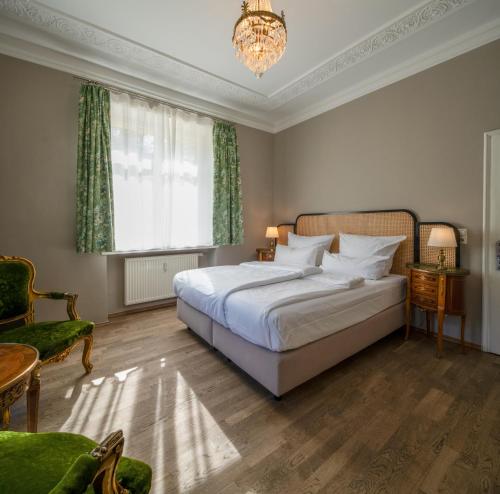 a bedroom with a large white bed and a chandelier at Villa Bleichröder in Heringsdorf