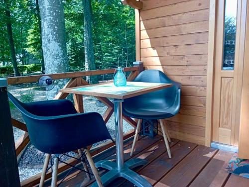 - une table et deux chaises sur la terrasse couverte d'une cabine dans l'établissement Roulotte Les Deux Geais, à Sainte-Opportune-du-Bosc