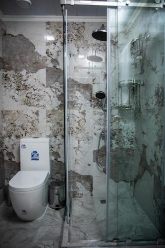 a bathroom with a toilet and a glass shower at Qadim Hotel in Samarkand