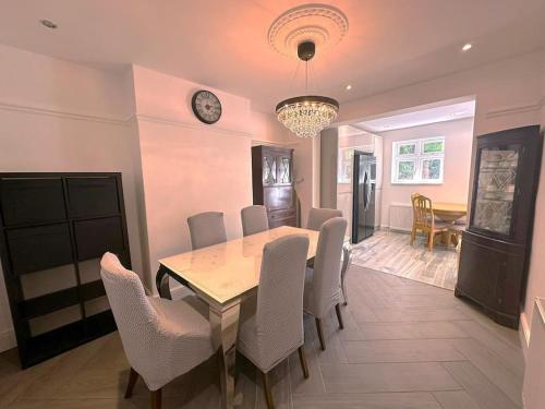 a dining room with a table and chairs and a clock at Luxurious House in Luton with free parking in Luton