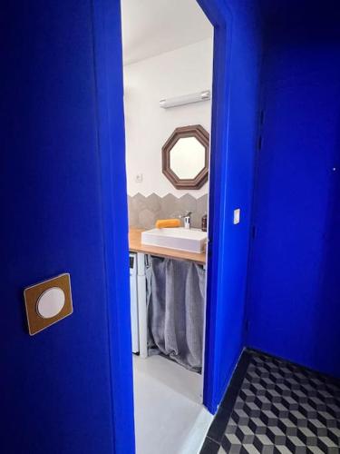 une porte bleue menant à une salle de bains avec lavabo. dans l'établissement Chambre proche Stade de France, métro à 5min, à Saint-Denis