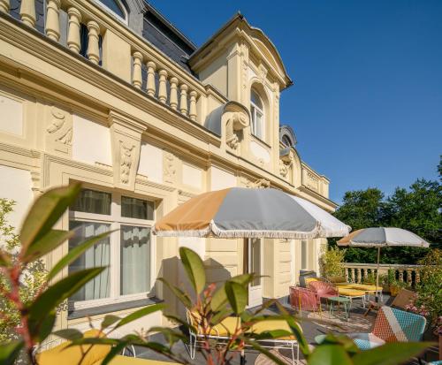 a building with tables and umbrellas in front of it at Villa Bleichröder in Heringsdorf