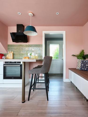 a kitchen with pink walls and a chair at a counter at Whimsical Haunt in West Malling