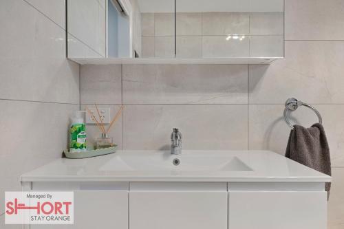 a white sink in a white tiled bathroom at Conservatorium Villa 1 in Orange