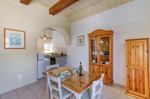 a kitchen and dining room with a wooden table and chairs at Villagg tal-Fanal in Għasri