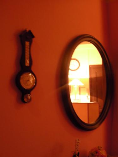 a mirror hanging on a wall with a clock and a mirrorigunigun at Affittacamere Alla Stazione in Trieste