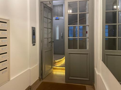 un couloir avec une porte ouverte et un escalier jaune dans l'établissement Prince's Terrace 2 bdr bth AC lift terrace garage Odéon Luxembourg, à Paris