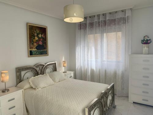 a white bedroom with a bed and a window at Casa del Parque in Pereruela
