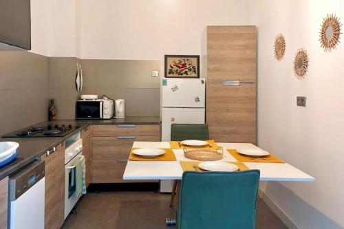 une cuisine avec une table, des chaises et un réfrigérateur dans l'établissement Le jasmin, Gentilly Paris Zone 2, à Gentilly
