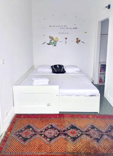 une chambre avec un lit blanc et un tapis dans l'établissement Le jasmin, Gentilly Paris Zone 2, à Gentilly