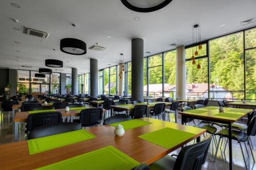 a restaurant with tables and chairs and large windows at Silesia Krynica in Krynica Zdrój