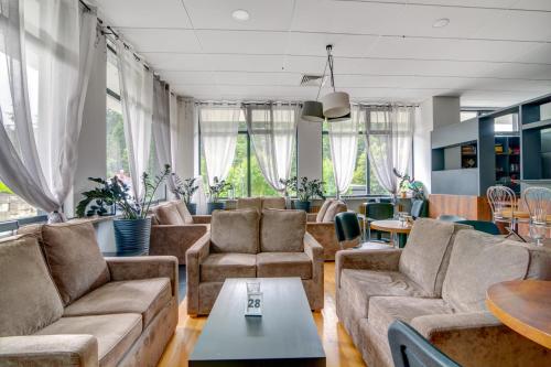 a living room with couches and tables and windows at Silesia Krynica in Krynica Zdrój
