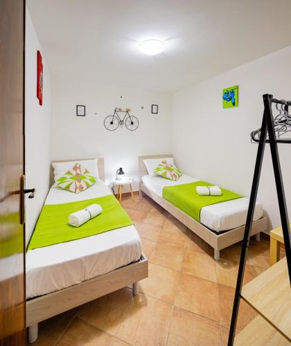 two beds in a room with green sheets at Carmine House in Monreale