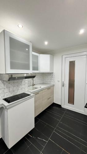 Il comprend une cuisine avec des placards blancs et du carrelage noir au sol. dans l'établissement Chaleureux t1 Aiguebelle, à Randens