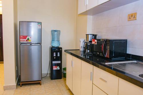 a kitchen with a refrigerator and a microwave at Elegant 2 BR Apartment Kileleshwa - Free Netflix, Parking, Superfast WIFI, Views of Arboretum in Nairobi