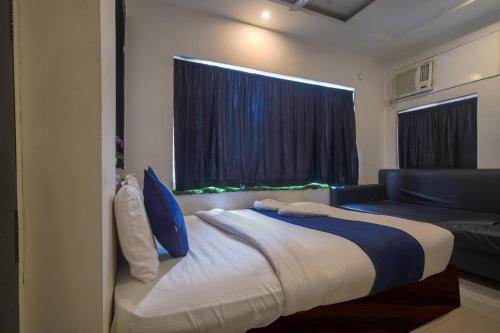 a bedroom with a bed and a couch and a window at Hotel Satyug Inn in Ujjain