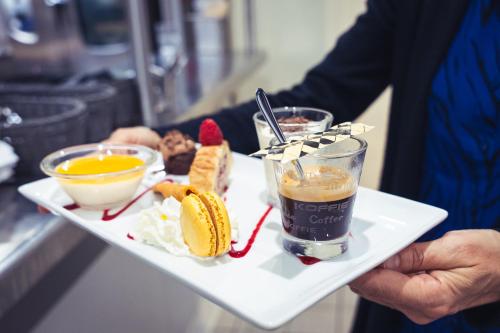 a person holding a plate of food with a drink at Brit Hotel Confort Manosque Cadarache in Manosque