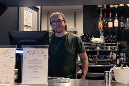 a man standing behind a counter in a coffee shop at Brit Hotel Confort Manosque Cadarache in Manosque
