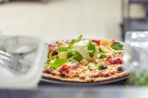 a pizza on a plate on a table at Brit Hotel Confort Manosque Cadarache in Manosque