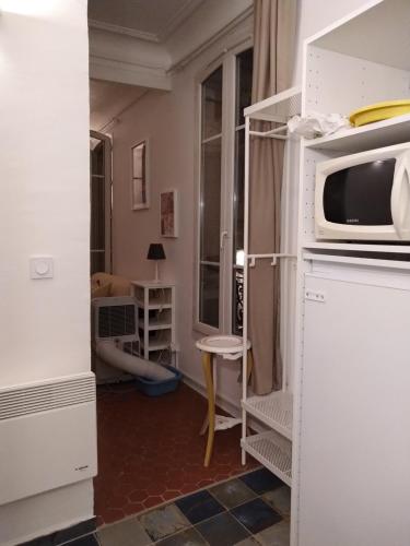 une cuisine avec un four micro-ondes au-dessus d'un comptoir dans l'établissement Appartement provençal - Avignon intra-muros, à Avignon