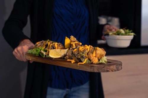a person holding a plate of food on a wooden board at Brit Hotel Confort Manosque Cadarache in Manosque