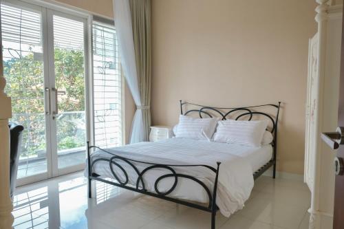 a bedroom with a wrought iron bed with white pillows at The Green Wowi Torto, 5 BR, swimming pool in Bandung