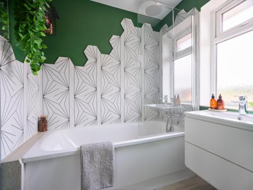 a bathroom with a white tub and a green wall at Whimsical Haunt in West Malling