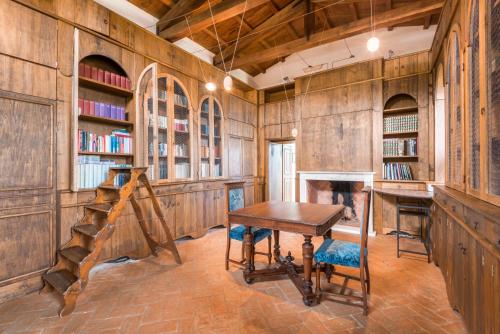 カッラーラにあるConvento La Perlaの木製の壁とテーブル、暖炉のある図書室