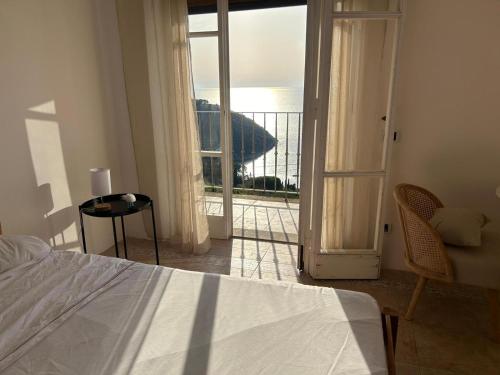 a bedroom with a bed and a door to a balcony at Villa Velta Sea Sunset in Porto Santo Stefano