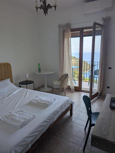 a bedroom with a bed and a table and a balcony at Villa Velta Sea Sunset in Porto Santo Stefano