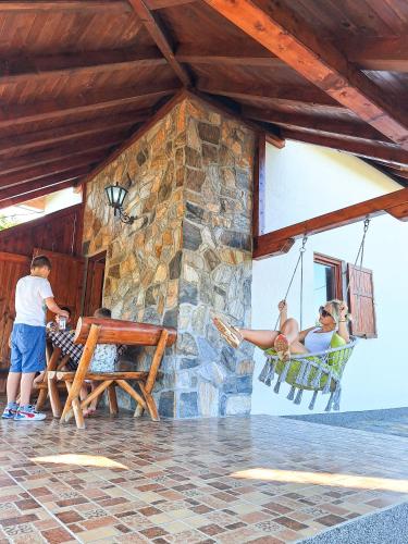 a couple of people sitting in a hammock outside a building at Planinska kuća Radulović in Goč