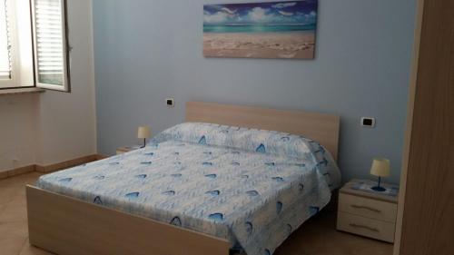 a bedroom with a bed with a blue comforter at Grazioso appartamento azzurro in Leuca