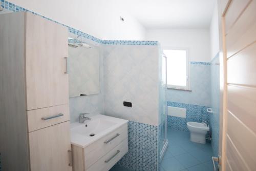 a blue and white bathroom with a sink and a toilet at Grazioso appartamento azzurro in Leuca