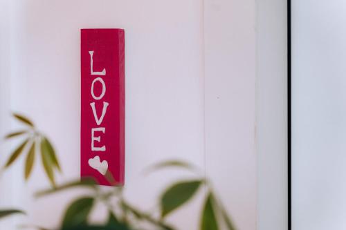 a red sign that says love next to a plant at Sleep & Fly Malpensa in Case Nuove