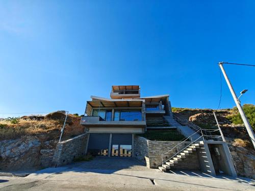 a house on top of a hill with stairs at Above Blue Villas in Plomarion