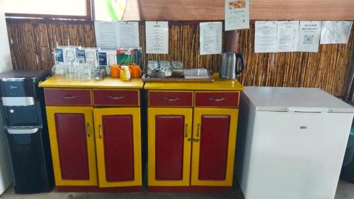 a kitchen with a yellow and red counter with drinks at Devocean Eco Adventure Lodge in Ponta do Ouro