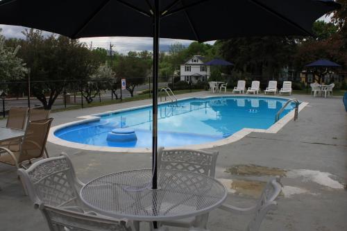 a table with an umbrella next to a swimming pool at Berkshire Inn in Pittsfield