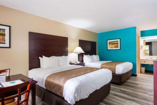 a hotel room with two beds and a desk at Quality Inn & Suites Rockingham in Rockingham