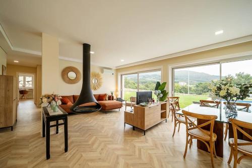 a living room with a fireplace and a dining room at Oliveiral Villa with River View, Heated Pool & Jacuzzi in Vila Nova de Cerveira