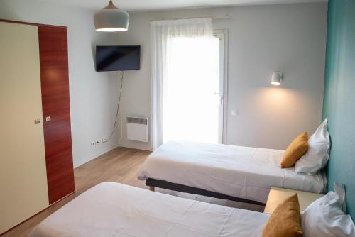 a hotel room with two beds and a television at Terres de France Brest in Brest