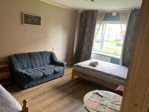 a living room with a blue couch and a window at 1-bedroom 2 big beds MV64 in Tartu