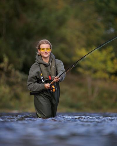 a person standing in a river holding a fishing rod at SCHLOSS Roxburghe, part of Destination by Hyatt in Kelso