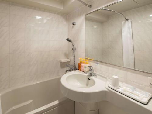 a bathroom with a sink and a tub with a mirror at Comfort Hotel Suzuka in Suzuka